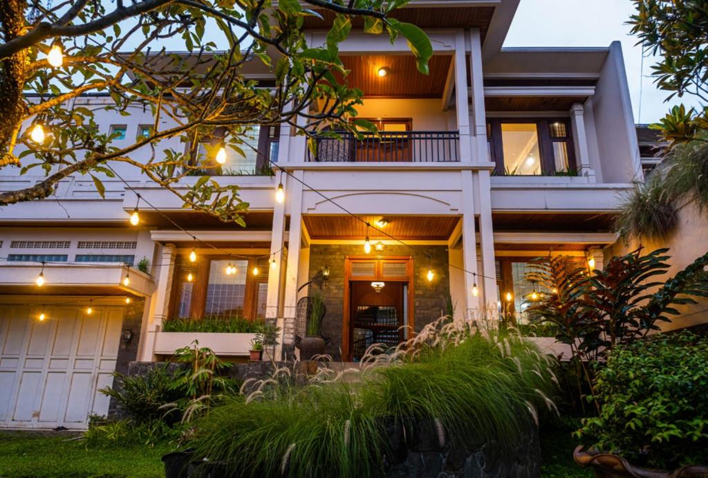une maison blanche avec des lumières à l'avant dans l'établissement Andaru Sukahaji - Perfect for Family and Friends, à Bandung