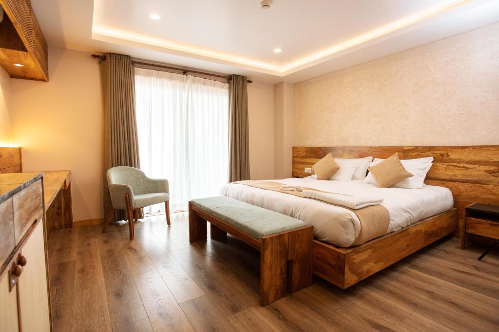 um quarto de hotel com uma cama e uma cadeira em HOTEL BHRIKUTI TARA em Catmandu