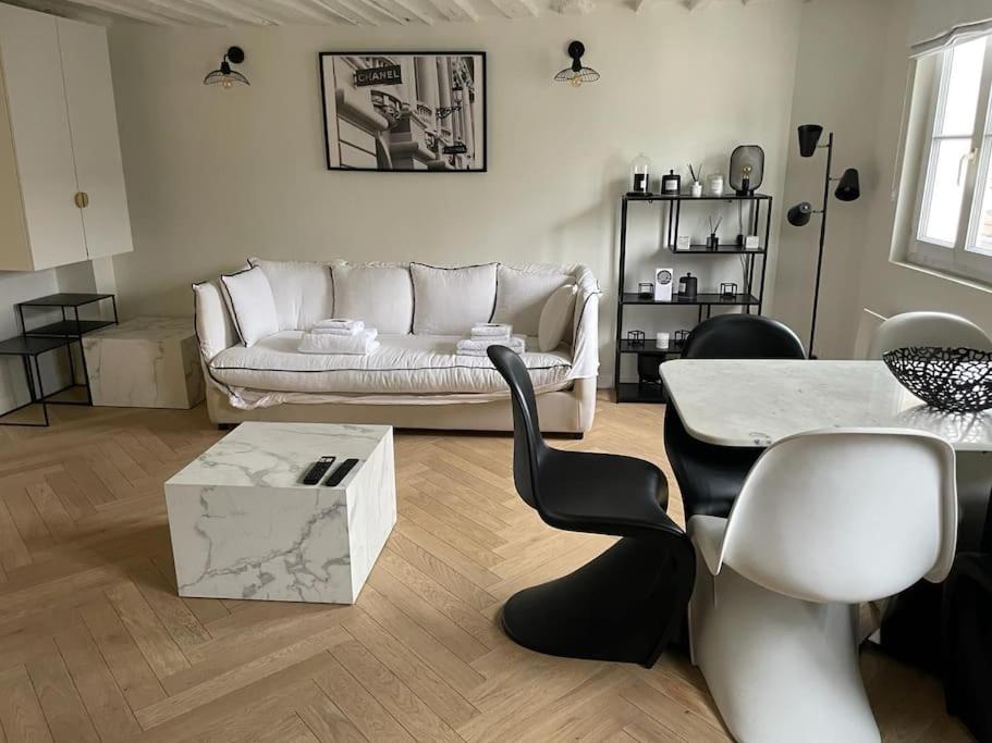 uma sala de estar com um sofá, uma mesa e cadeiras em Élégant Appartement près du Musée du Louvre et du Jardin des Tuileries em Paris