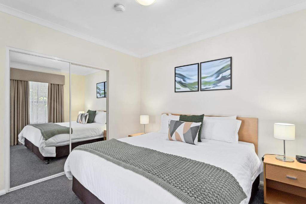 1 Schlafzimmer mit 2 Betten und einem Spiegel in der Unterkunft Northbridge Prime Location*2BR in Perth