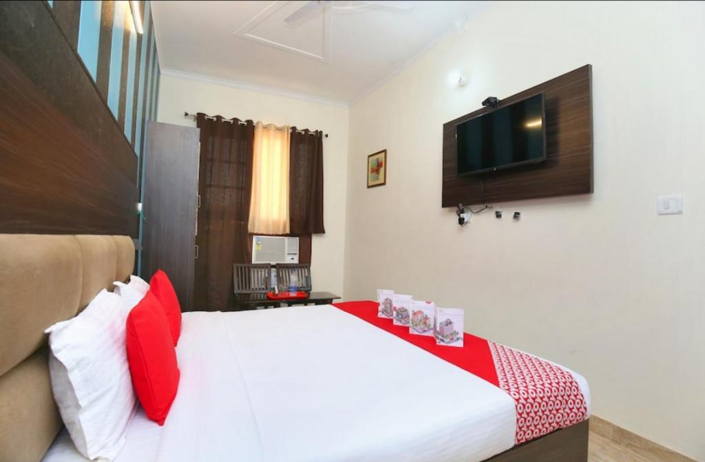- une chambre dotée d'un grand lit avec des oreillers rouges et blancs dans l'établissement Hotel Royal shades, à Chandigarh