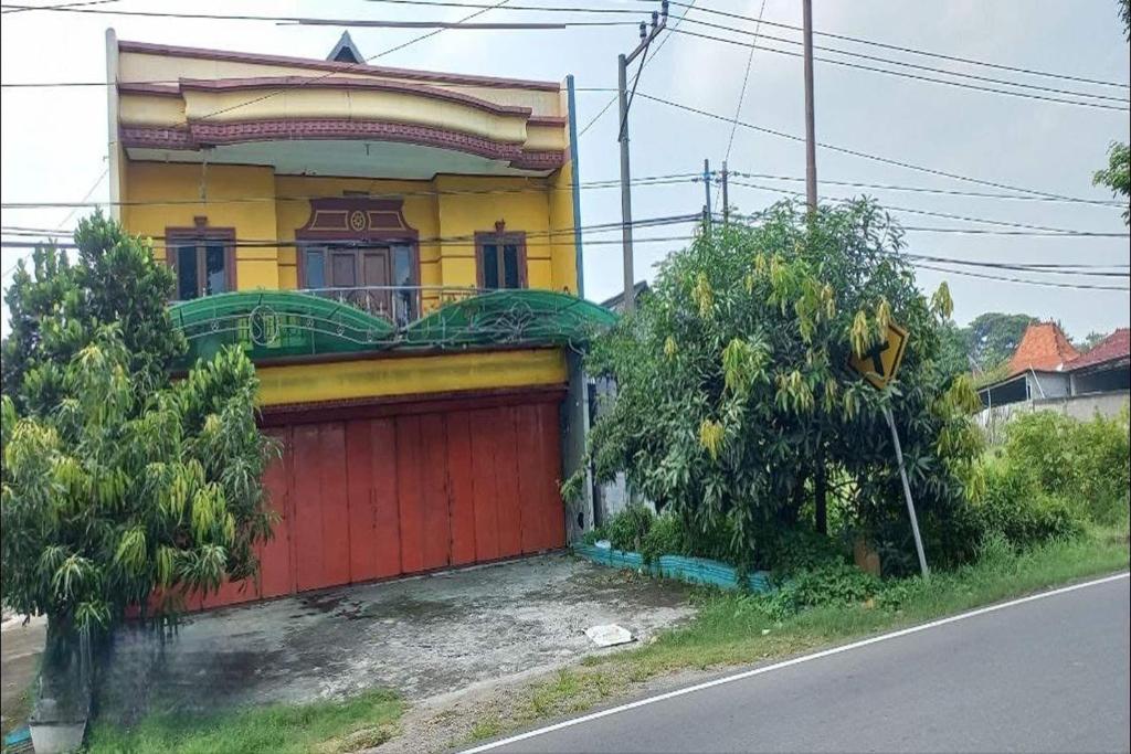 ein Haus mit einer roten Garage am Straßenrand in der Unterkunft OYO 93769 Setia Budi Guest House 2 in Sragen