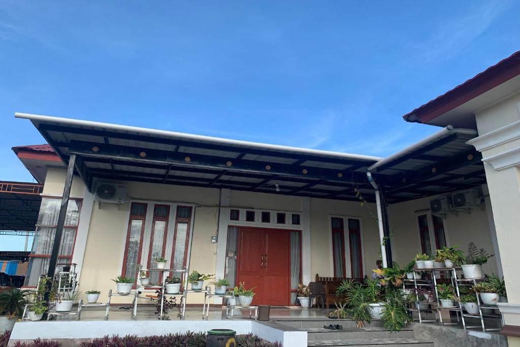 a house with a red door and tables and chairs at OYO 93778 Kost Hidayat Syariah in Laleng-balandae