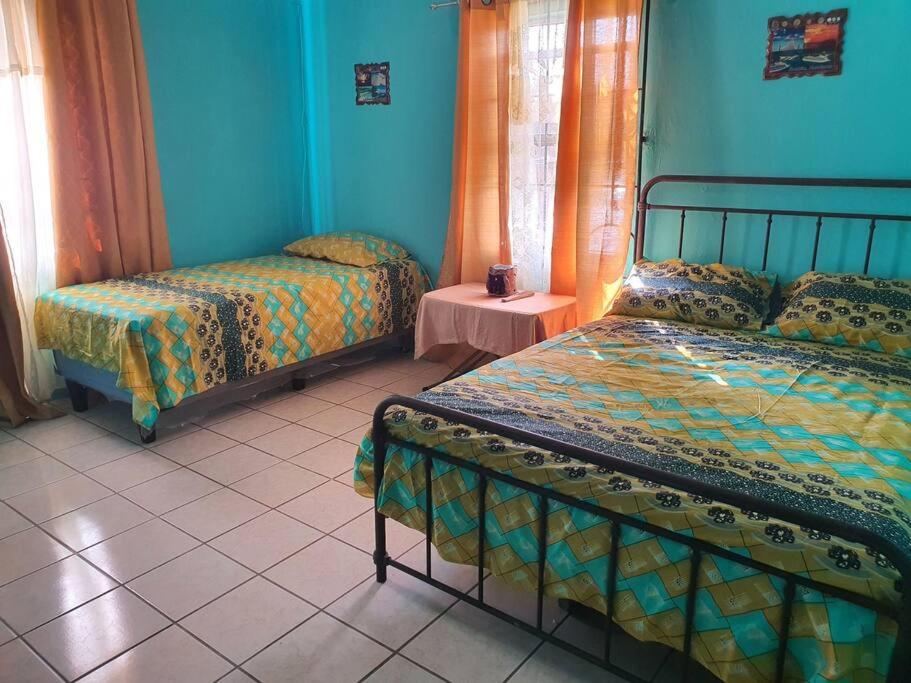 a bedroom with two beds and blue walls at House for 5 with vehicle included in Roatan in Coxen Hole