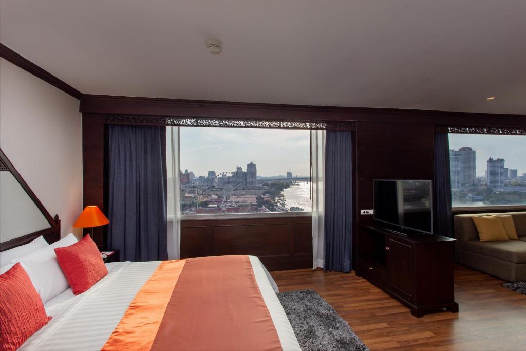 A king bedroom with broad river-facing windows and a separate sofa area.