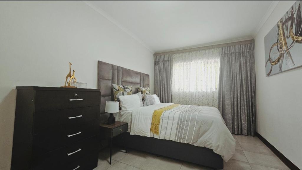 a bedroom with a bed and a dresser and a window at Bryanston Guest Cottage in Johannesburg