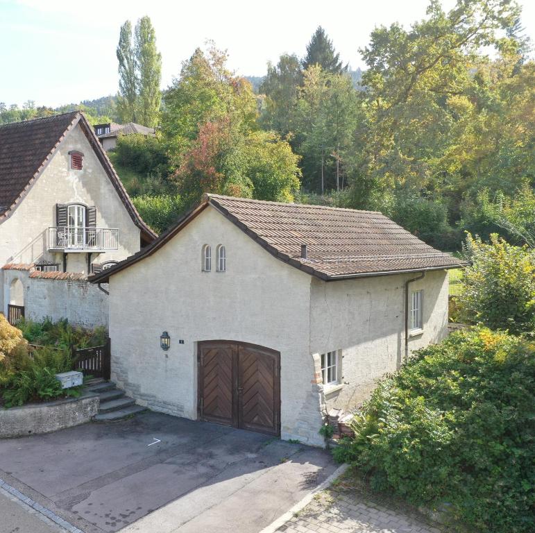 a white house with a garage and a driveway at peaceful tiny house near forest in Rorschacherberg