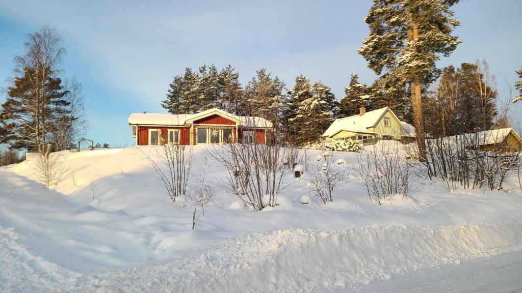 een huis op een heuvel bedekt met sneeuw bij Charming cottage in Forsa, Hudiksvall with lake view in Hudiksvall