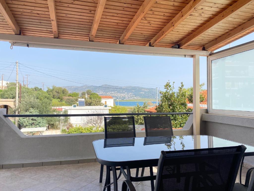 einen Balkon mit einem Tisch und Stühlen sowie einem großen Fenster in der Unterkunft Seaside Luxury Apartments in Porto Rafti