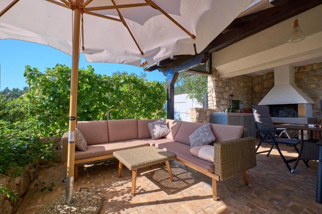 a couch and an umbrella on a patio at Amazing house, 20 m from the beach, 80 m2 in Martinšćica