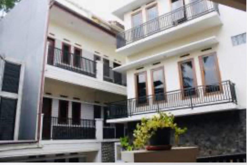 a large white building with balconies and a potted plant at Hotel O Qq Kost Near Pantai Kebesaran Beach in Laleng-balandae