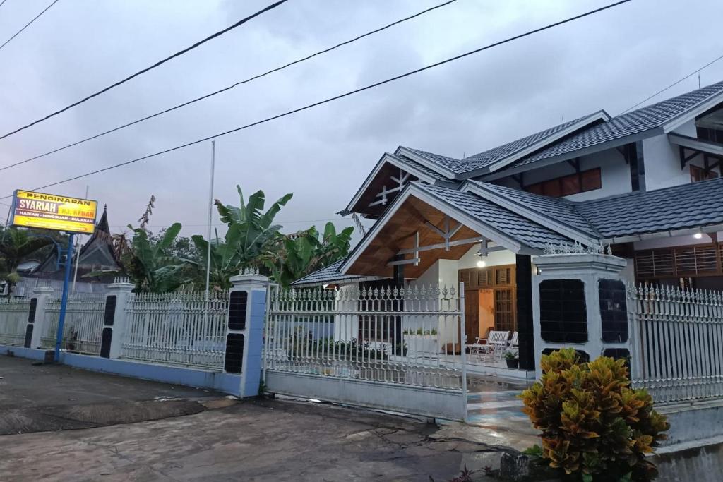 a house with a white fence in front of it at OYO 93706 Penginapan Syariah Hj. Kenan in Bukittinggi