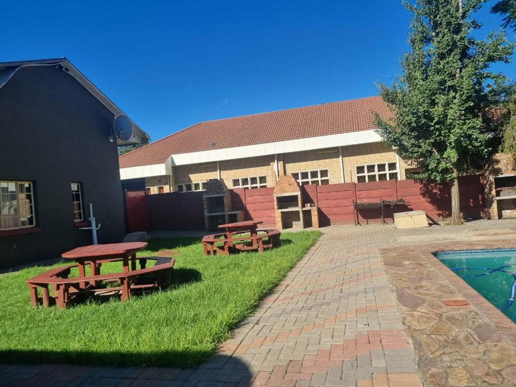 a building with picnic tables and a swimming pool at De Prince Lodge in Vereeniging