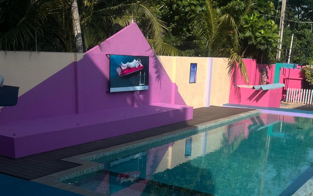 eine lila Bank neben einem Pool mit einem Gemälde in der Unterkunft Lost Planet Midigama in Galle