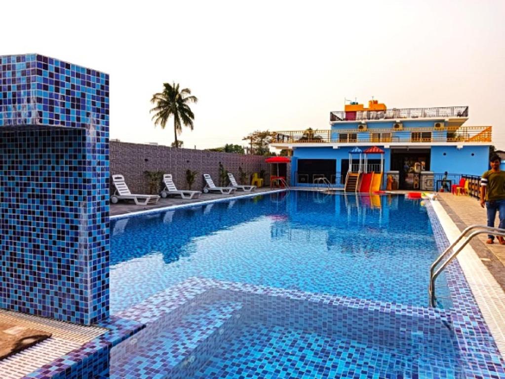 a large swimming pool with chairs and a building at THE PELICAN BEACH RESORT in Mandarmoni