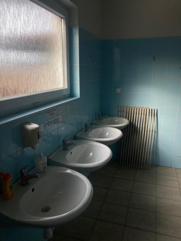 three sinks in a bathroom with blue walls and a window at Autokemp s koupalištěm in Nový Jičín