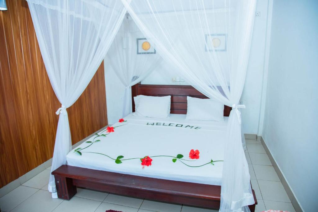 a bedroom with a white bed with red flowers on it at Ocean of Life Ayurveda Hotel in Induruwa