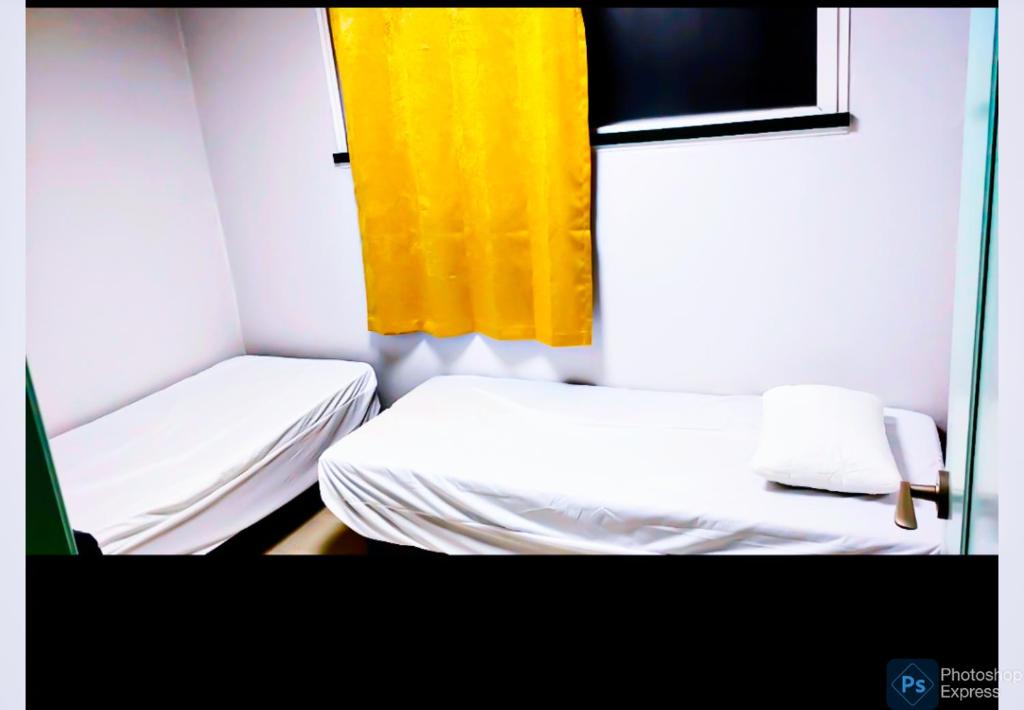 um pequeno quarto com duas camas e uma cortina amarela em Subhanallah guest house em Yangsan