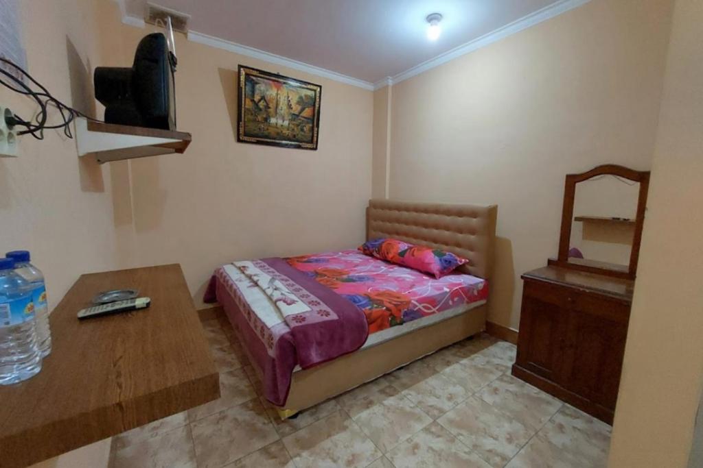 um quarto com uma cama, uma secretária e uma televisão em OYO 93757 Rasya Homestay em Midang