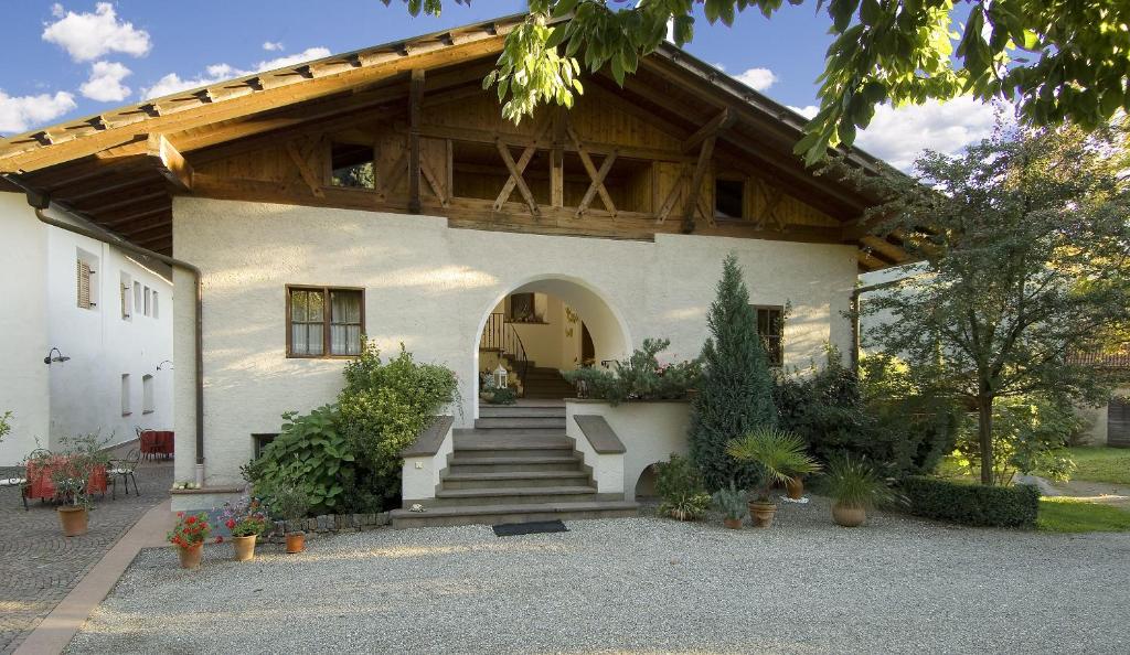 a white house with a wooden roof and stairs at Apartments Gasserhof in Lagundo