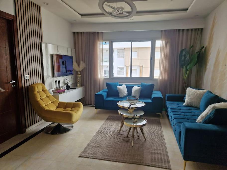 uma sala de estar com um sofá azul e uma cadeira amarela em Appartement proche de la plage à 200 M restaurant Piccolino em Dar el Koudia