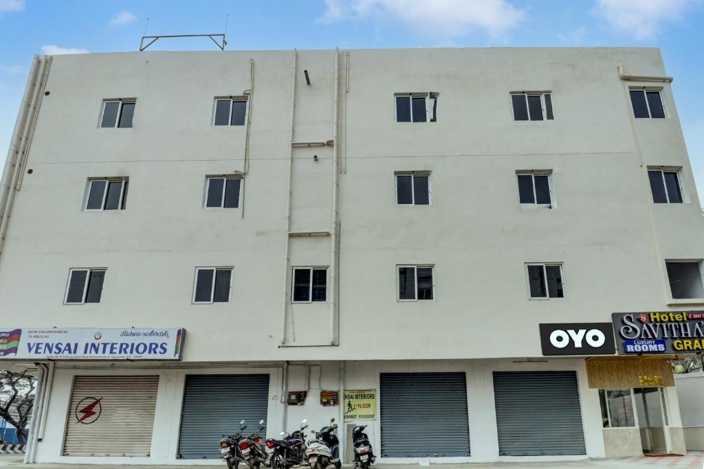 a white building with windows and motorcycles parked in front at OYO Hotel Savitha's Grand in Vijayawāda