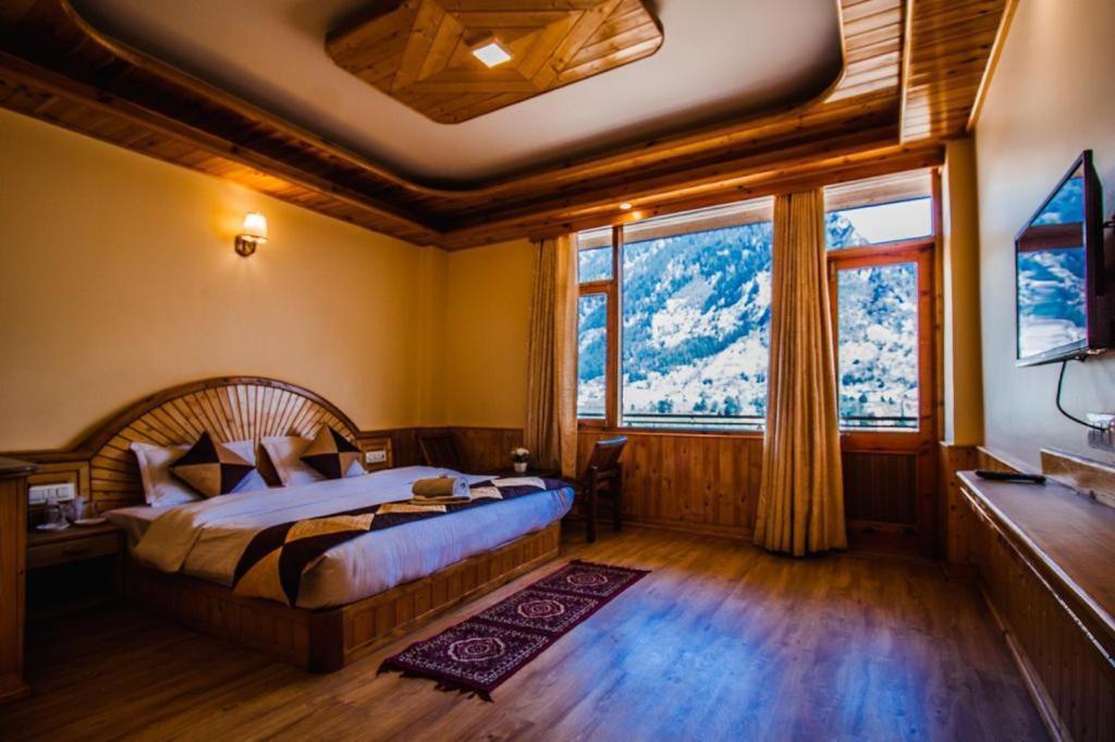 1 dormitorio con cama y ventana grande en Manali Mountain Resort en Manāli