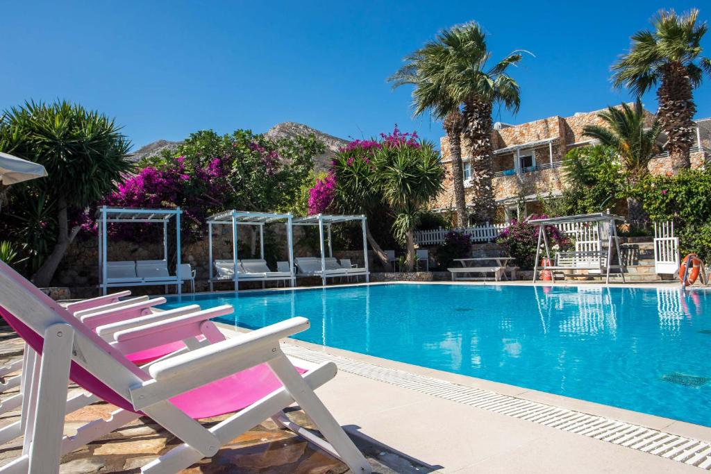 a swimming pool with chairs and palm trees at Hotel Irini in Livadia