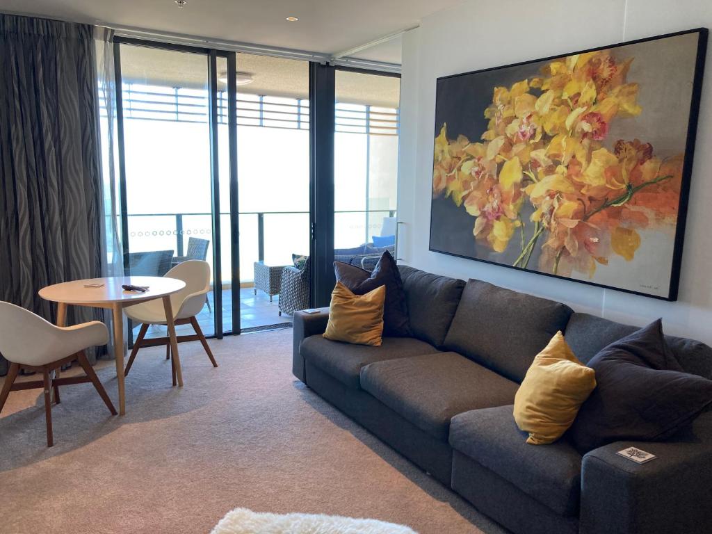 uma sala de estar com um sofá e uma mesa em Mon Komo Seaview Privately Owned Apartment em Redcliffe