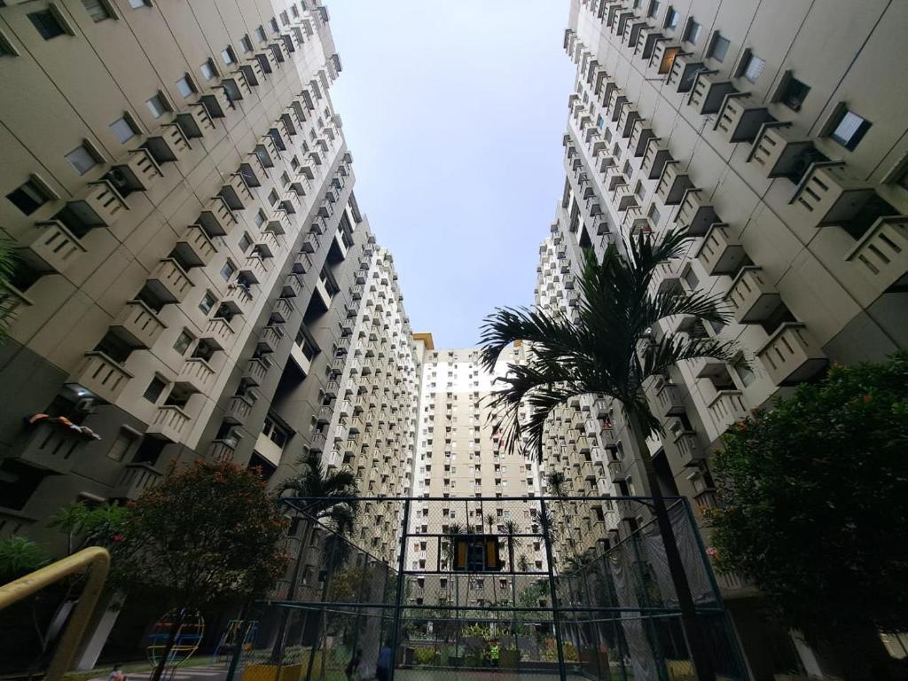 ein hohes Gebäude mit einer Palme davor in der Unterkunft Capital O 93743 Apartement Gateway Cicadas By Scm Property in Bandung