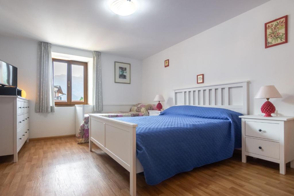 a bedroom with a blue bed and a window at DolomiApartments - Appartamento Girasole in Predazzo