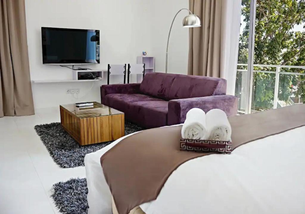 sala de estar con cama y sofá púrpura en Three Storey Garden Home at Bukit Gambir 18ppl, en Gelugor