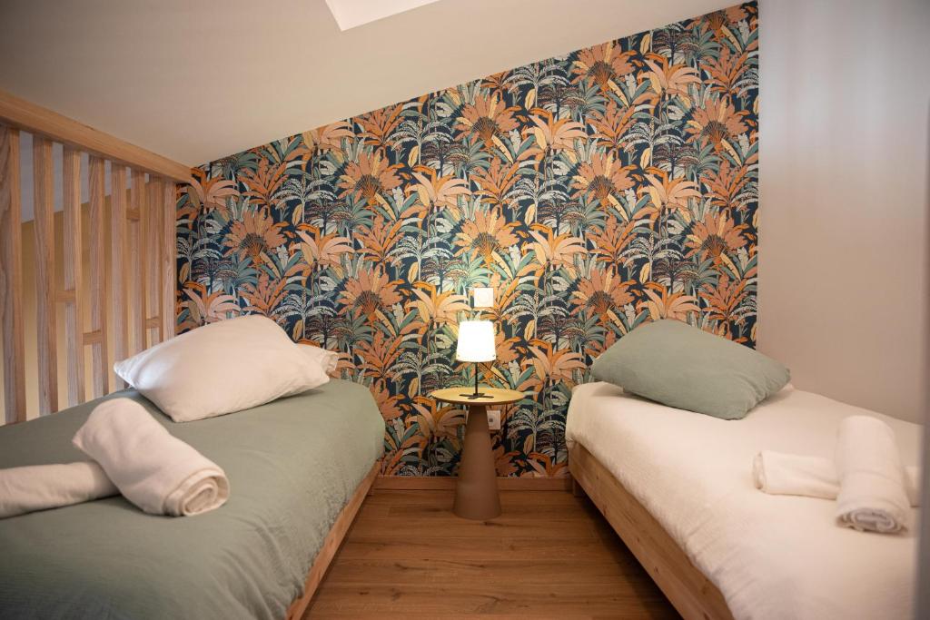 mały pokój z 2 łóżkami i tapetą w obiekcie La maison rue Nadaud, au pied des remparts w Carcassonne