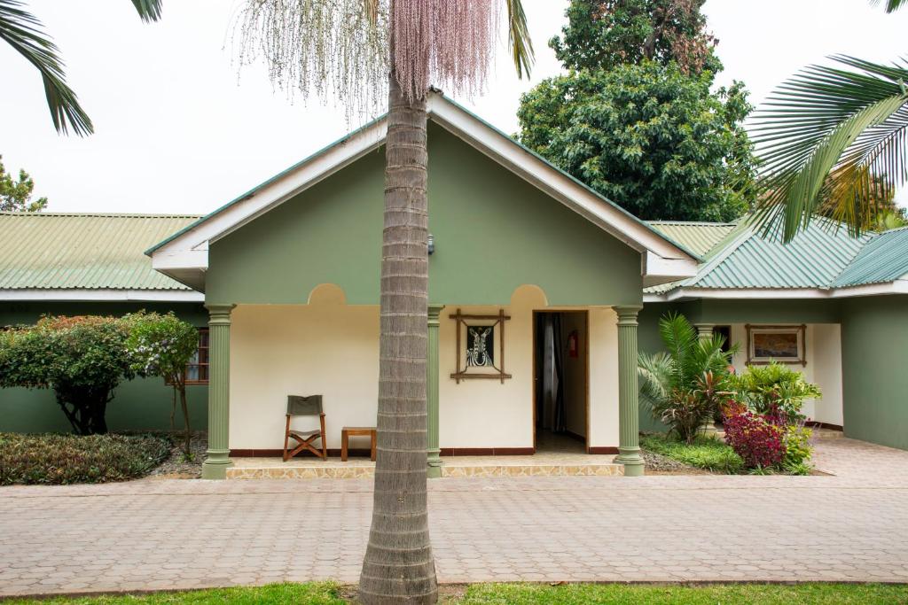 a house with a palm tree in front of it at 3 Degrees Hotel in Arusha