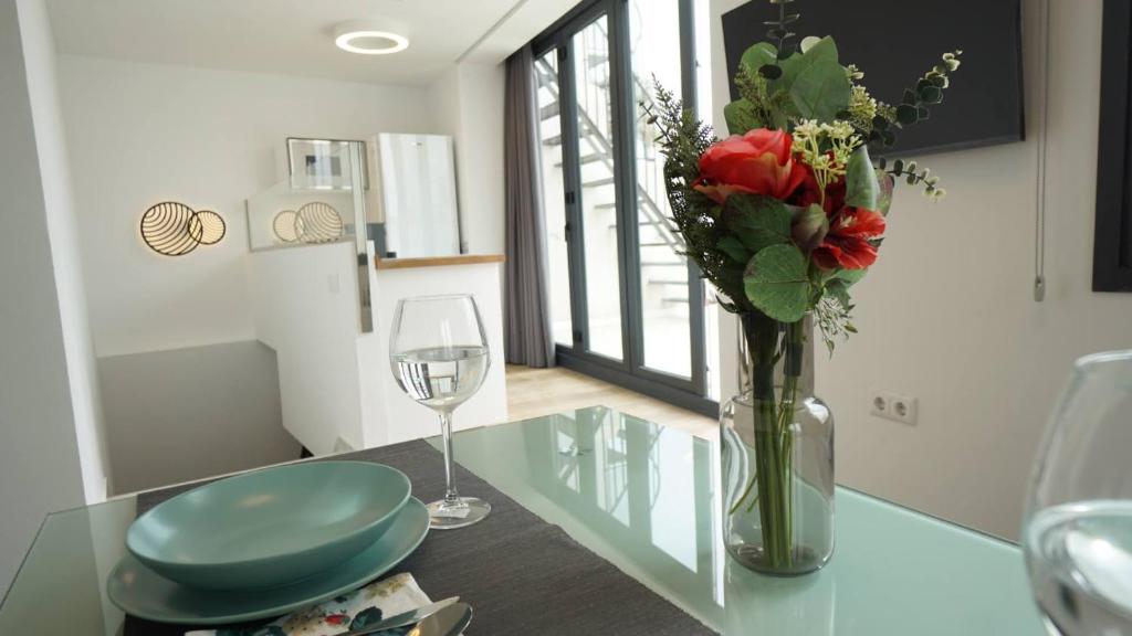eine Vase aus Blumen und ein Glas Wein auf dem Tisch in der Unterkunft RentalSevilla Cardenal Cervantes in Sevilla
