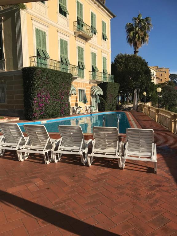 un groupe de chaises longues assises à côté d'une piscine dans l'établissement Hotel Miramare, à Imperia