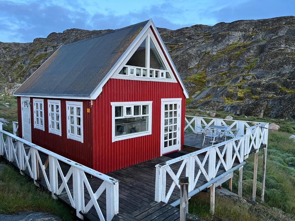 a red house on a boardwalk in front of a mountain at Hvalkigger huset in Ilulissat