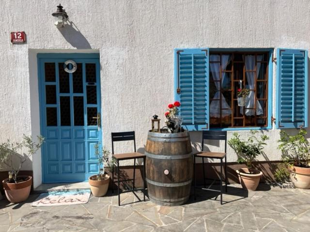 a building with a blue door and a barrel and chairs at Istrian house Mojca in Koper