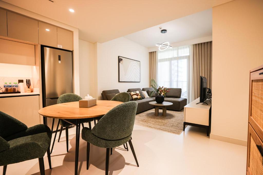 een woonkamer met een bank en een tafel en stoelen bij Tranquil 1BR Haven in the Heart of Vista Bliss - P1AB01 in Dubai