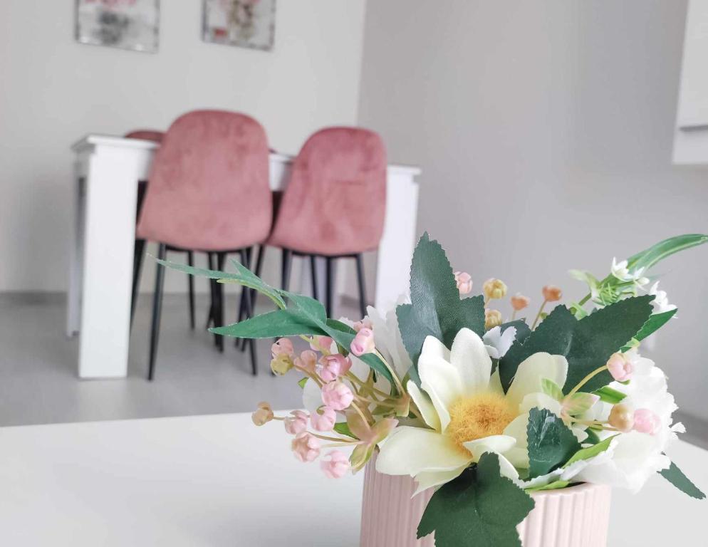 een vaas met bloemen op een tafel met twee stoelen bij DiP HOME APARTMENTS in Pomorie