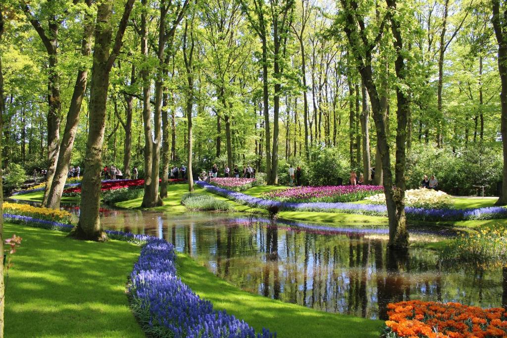 einen Garten mit einem Teich und vielen Blumen in der Unterkunft Bed and Breakfast Ineke en John in Hoofddorp