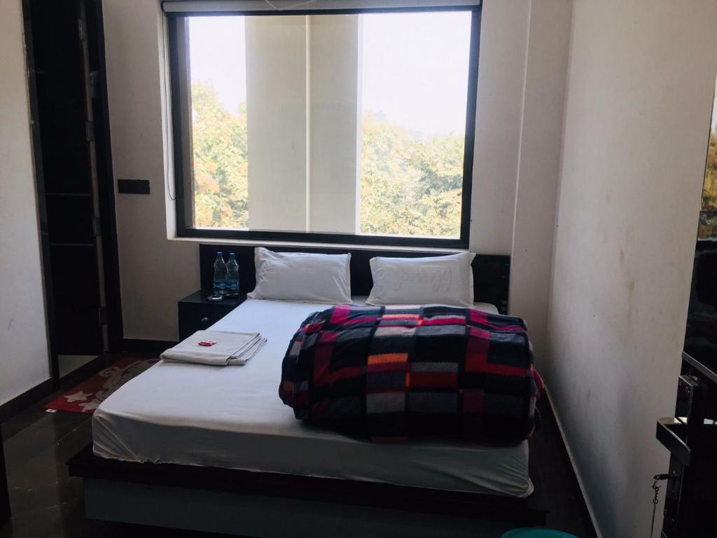 Bett in einem Zimmer mit einem großen Fenster in der Unterkunft RV Lodge in Bulandshahr
