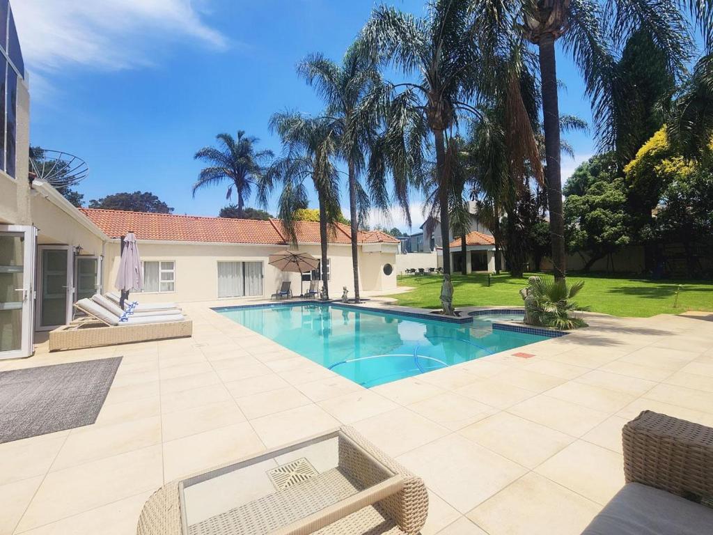 a swimming pool in a yard with palm trees at Villa Reis - The Villa of Kings in Bedfordview