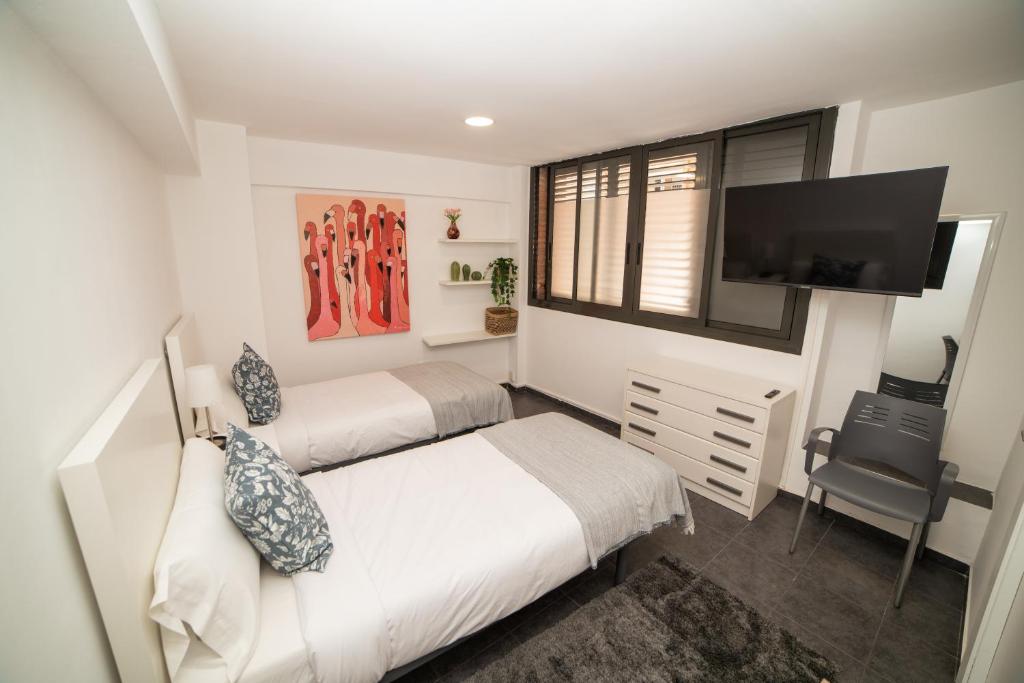 a bedroom with two beds and a flat screen tv at Barcelona Apartment Near Park Güell in Barcelona