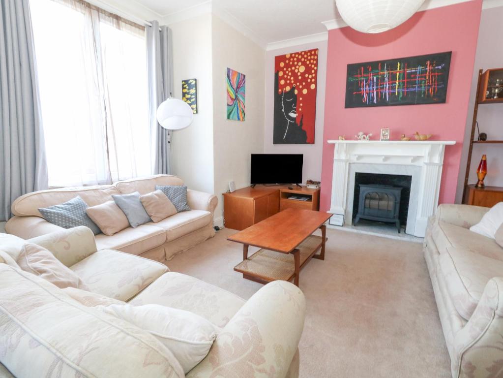 a living room with two white couches and a fireplace at Victorian Town House in Weymouth