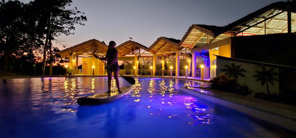 a man standing on a paddle board in a pool at night at Annabel's Resort in Ferrol