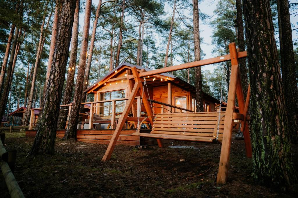a wooden cabin in the woods with a tree at WYPOCZYWANKO DOMEK PIERWSZA LINIA BRZEGOWA in Borsk