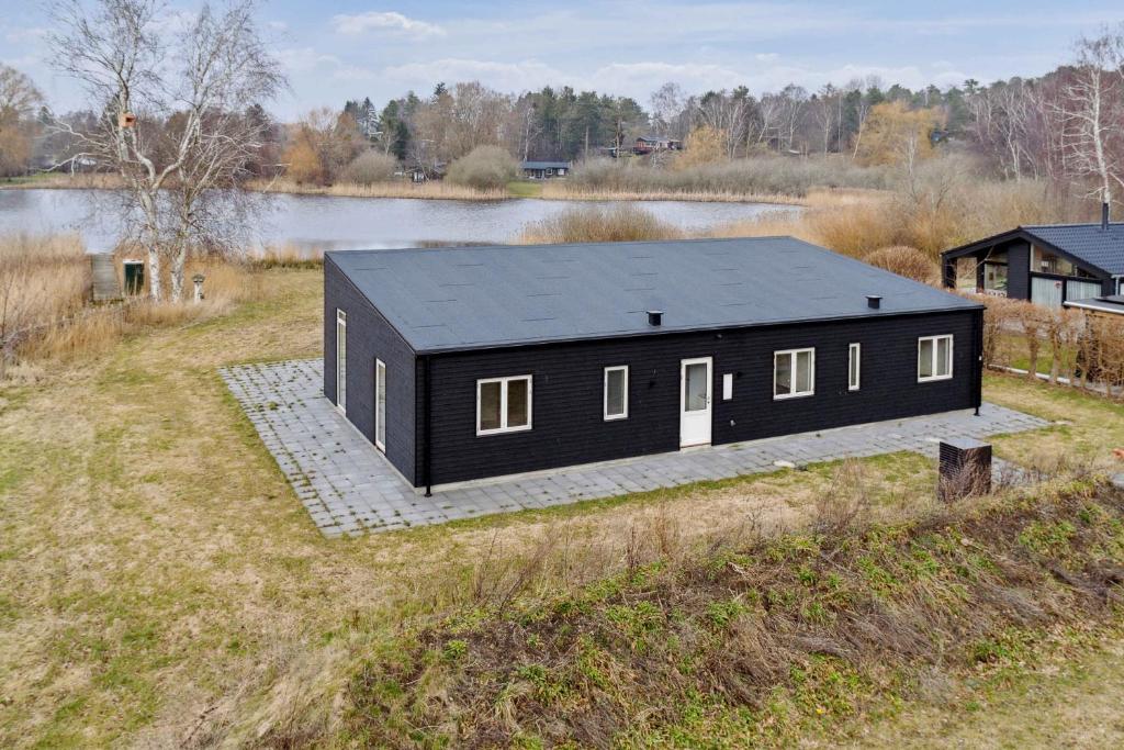 a black house with a black roof on a field at Brand New And Modern Summer House In Kulhuse in Jægerspris