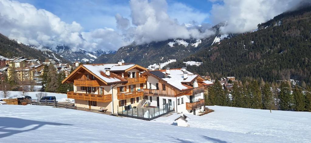 a large wooden house in the snow in the mountains at Casa Davarda in Vigo di Fassa