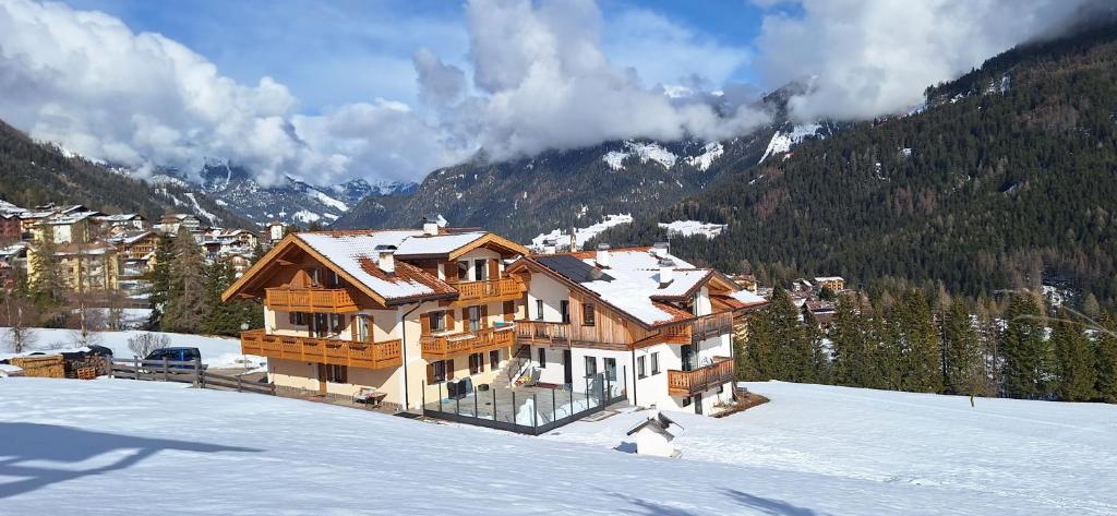 duży drewniany dom w śniegu w górach w obiekcie Casa Davarda w mieście Vigo di Fassa